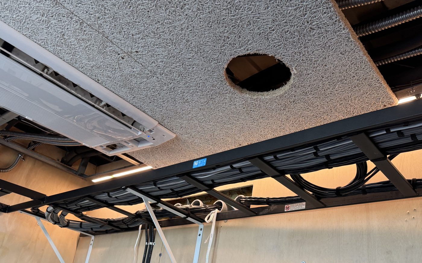Ceiling-mounted ladder rack carrying black cable bundles dressed and tied at regular intervals