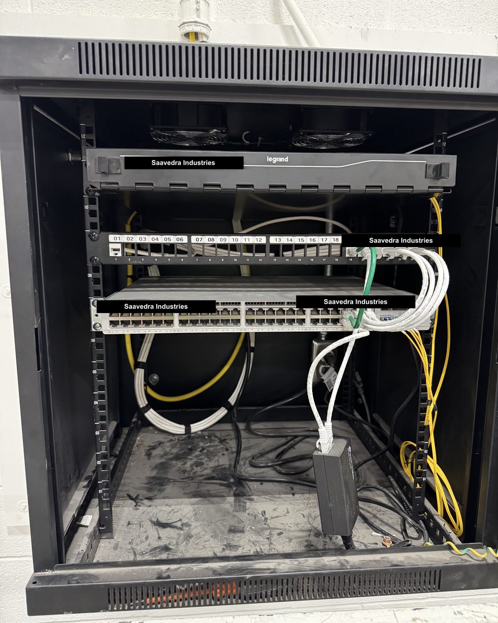 Open server rack with a fibre enclosure, numbered patch panel, network switch, and dressed cables